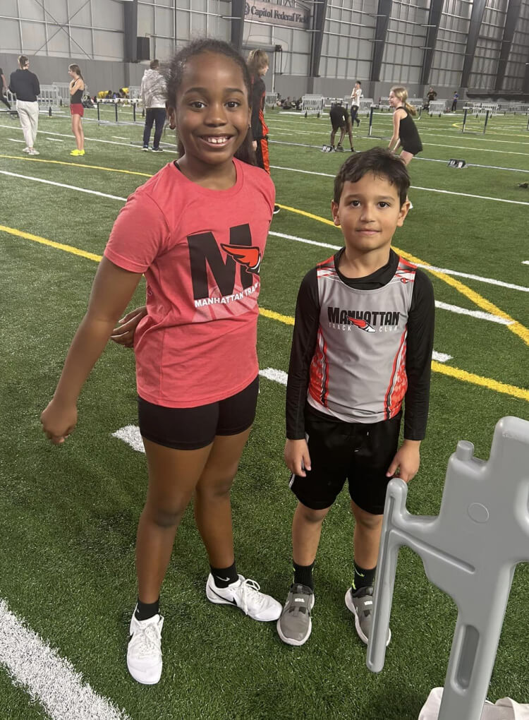 two kids in MTC posing for picture on turf